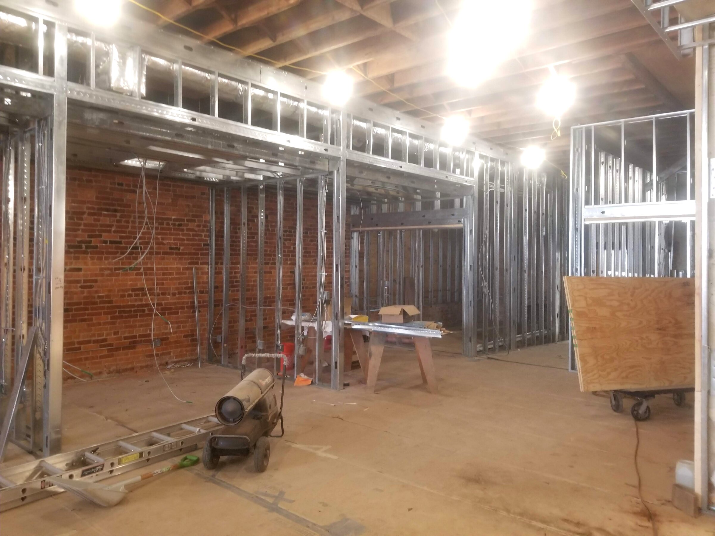 Office walls taking shape with metal framing and exposed brick